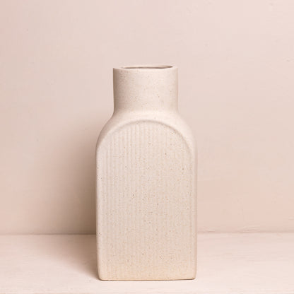 Minimalistische, rechthoekige vaas met afgeronde hoeken, uitgevoerd in een zachte zandkleur en voorzien van een subtiele ribbelstructuur.