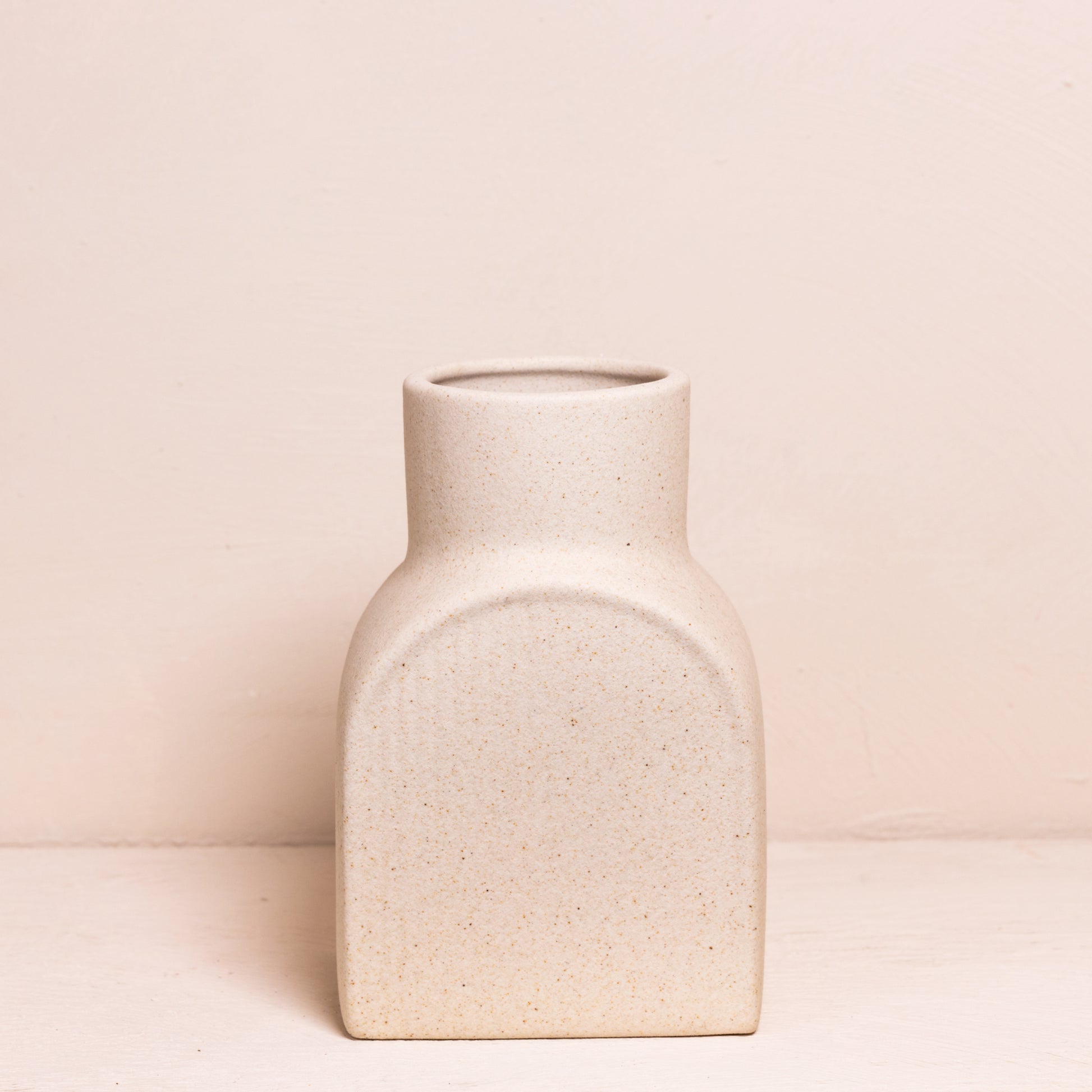 Kleine, rechthoekige vaas met afgeronde hoeken, minimalistisch uitgevoerd in een neutrale zandkleur met een subtiele ribbelstructuur.